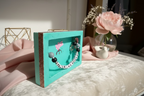 Small turquoise book with decorative elements on a wooden surface