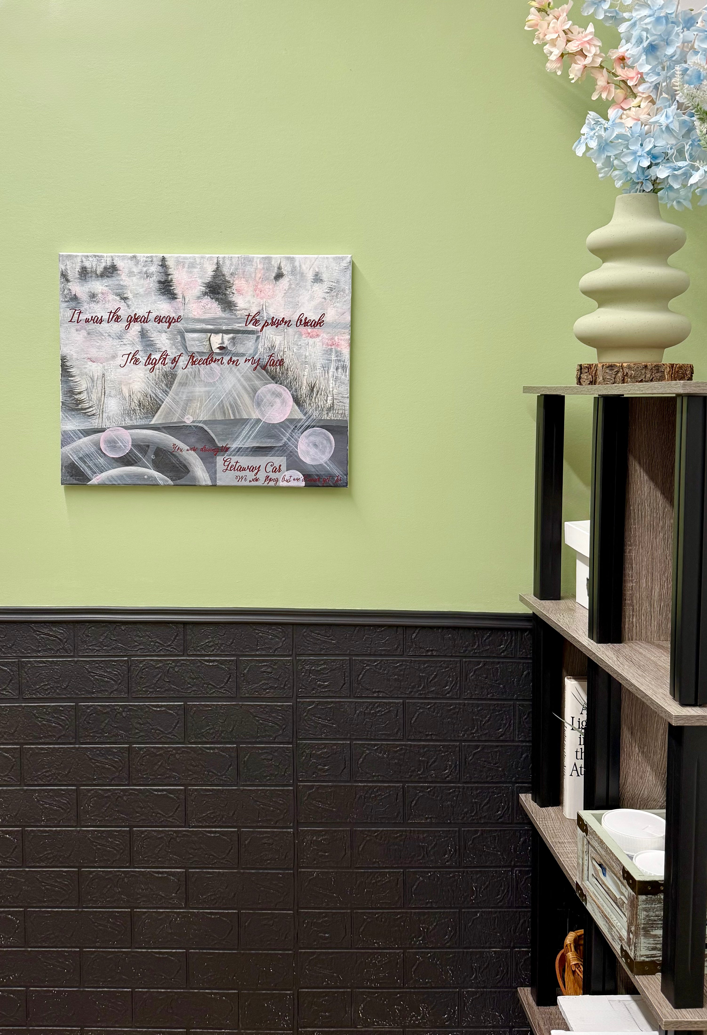 Room interior with a painting on a green wall and a shelf with decorative items.