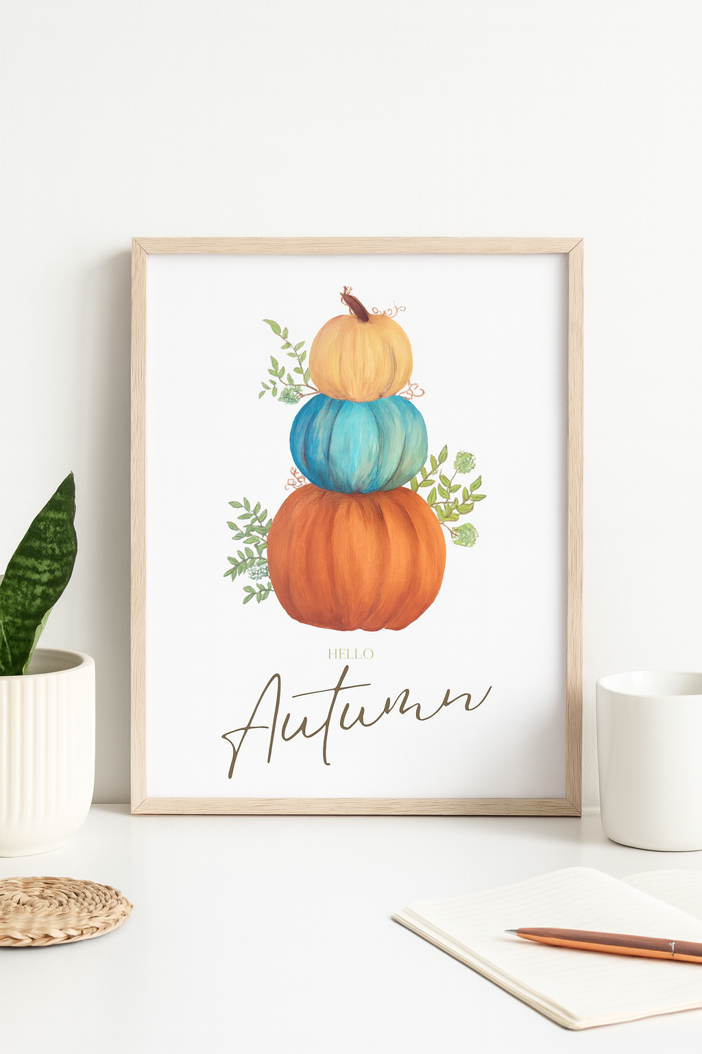 Framed artwork with pumpkins and 'Autumn' text on a white surface.