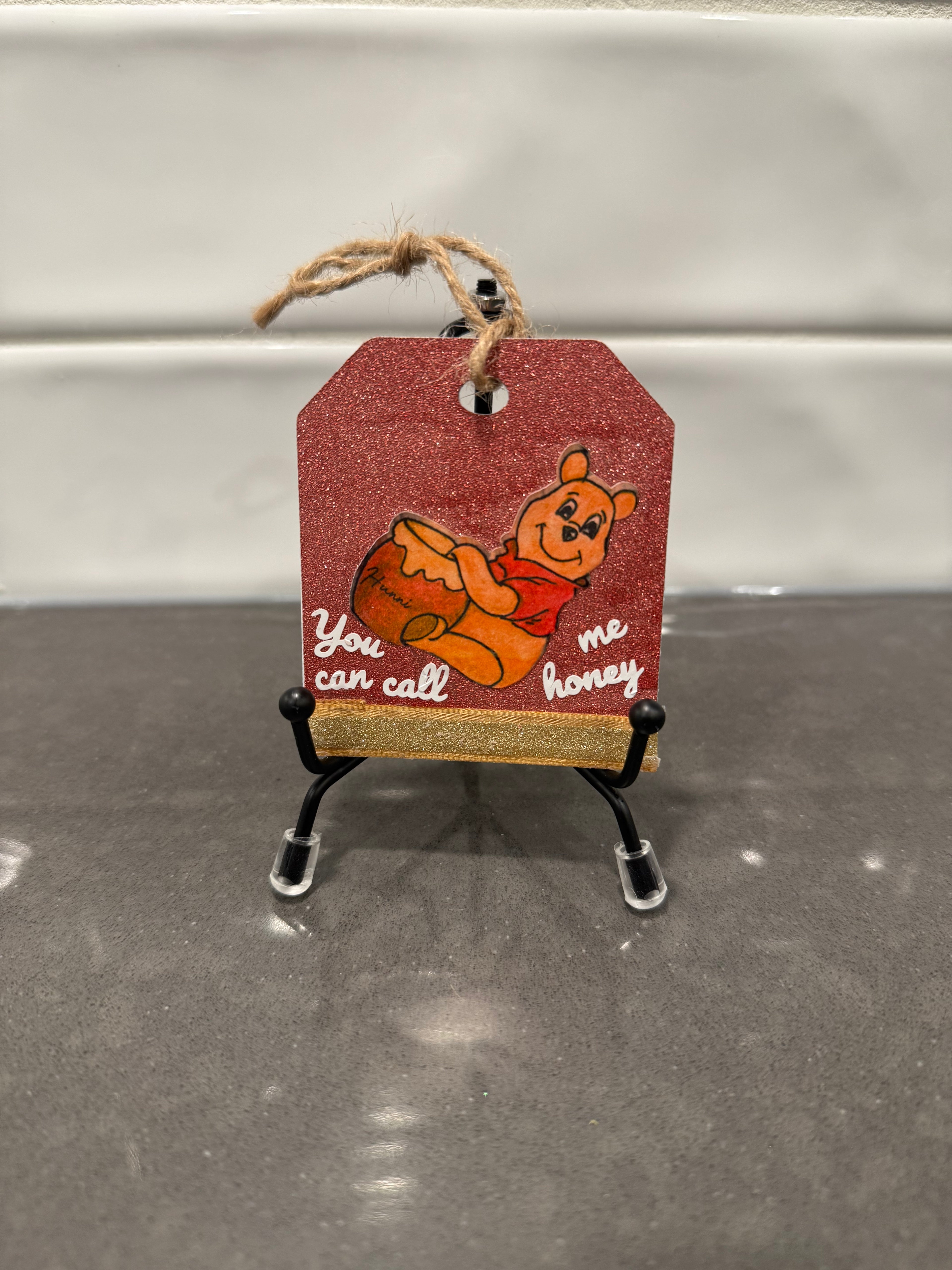 Decorative tag with a bear illustration and text on a stand against a neutral background