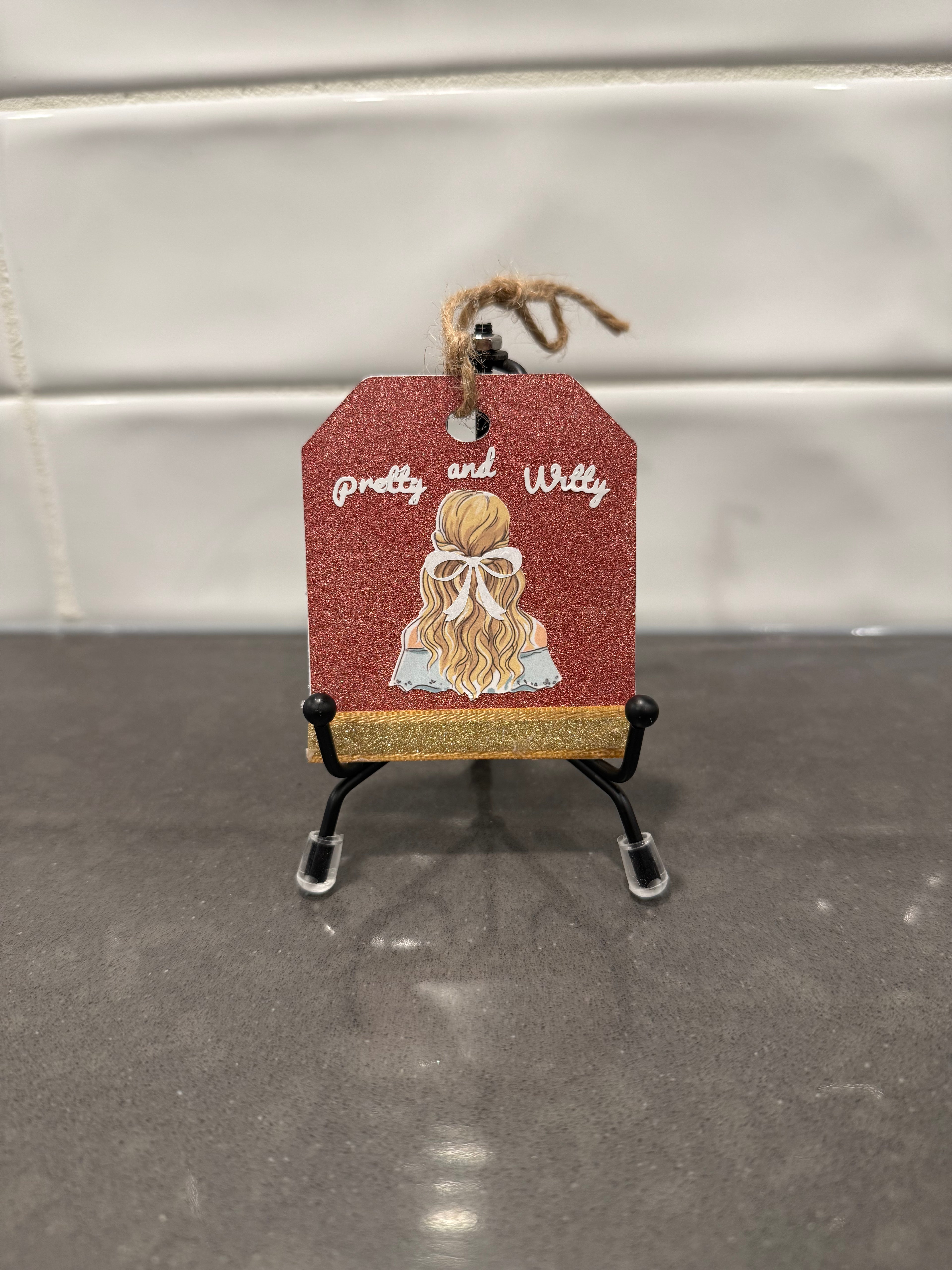 Decorative tag with a girl illustration and 'Pretty and Willy' text on a stand.