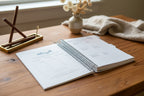 Open spiral-bound notebook on a wooden desk, rustic decor. 