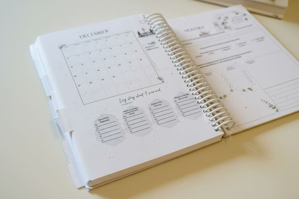 Spiral-bound planner open to a page with a December calendar and checklist on a wooden surface.