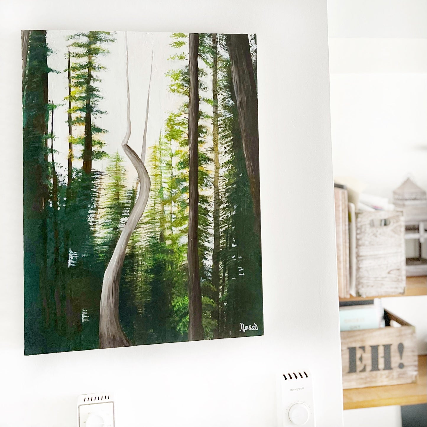 Forest painting on a white wall with a wooden shelf below