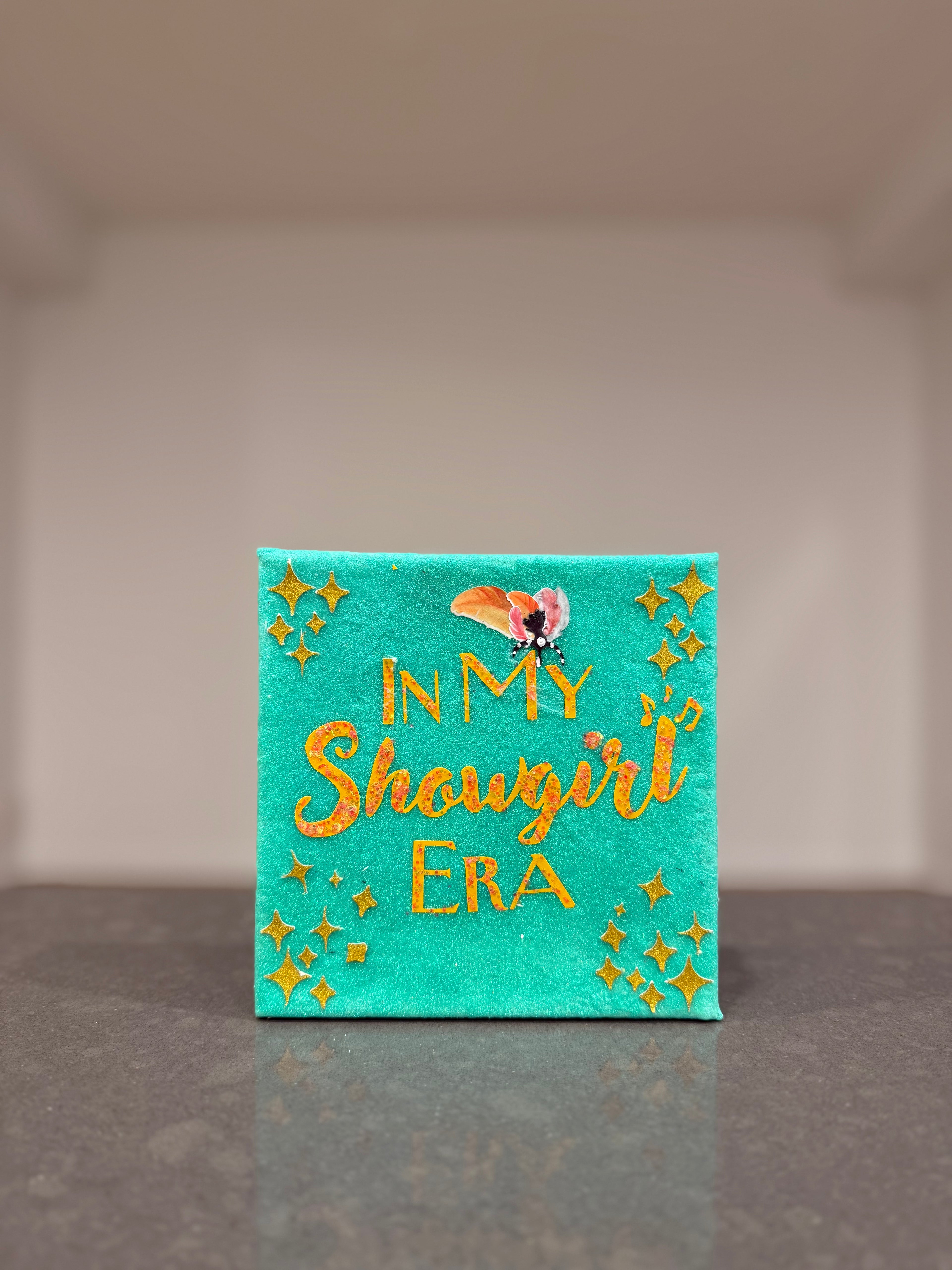 Turquoise canvas with 'In My Showgirl Era' text and decorative elements on a neutral background