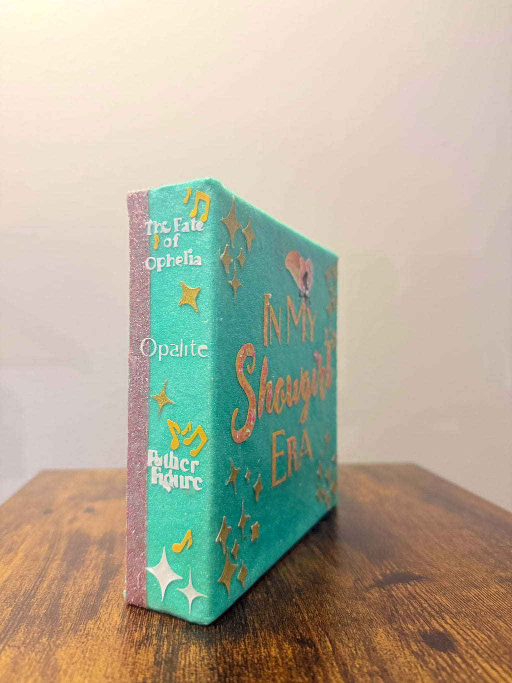 Decorative book with turquoise cover and pink spine on a wooden surface