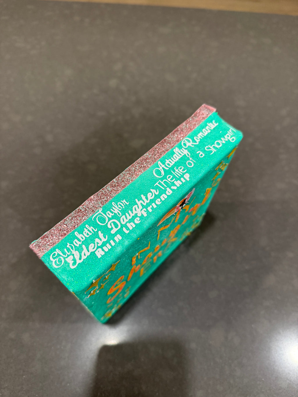 Teal book with gold text on a gray surface